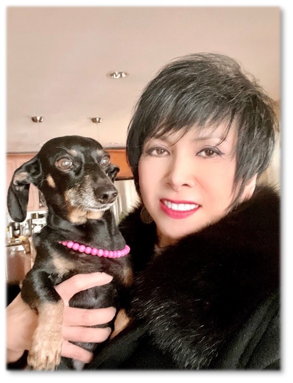 Photograph of blog post contributor Trang Bui holding small pet dog that is wearing a pink pearl collar