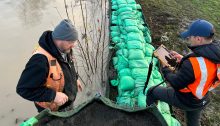 A photograph showing King County emergency management personnel assessing a levee.